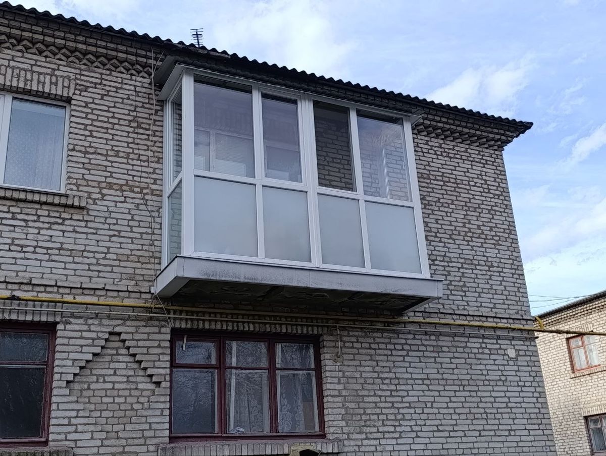 Балкон із білим ПВХ-заскленням і матовими нижніми панелями