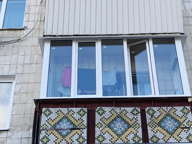 Біле засклення балкона від перил над мозаїчним парапетом