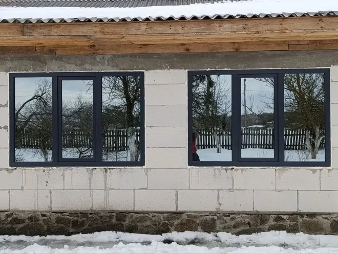 Стрічка темних металопластикових вікон у будинку з газоблоку — зимовий монтаж нашої бригади
