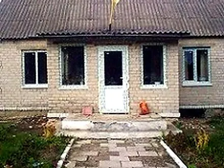 Ряд вікон і вхідні двері у довгому будинку з блоку