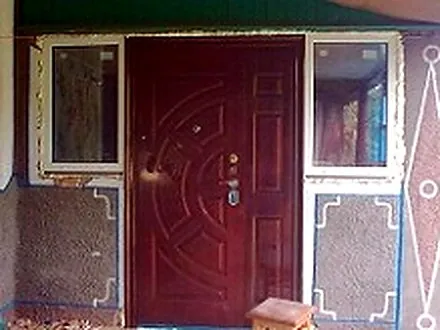 Вхідні металеві двері з боковими фрамугами у приватному будинку